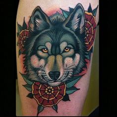 a tattoo with a wolf and flowers on it