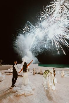 a bride and groom standing on a patio with fireworks in the background