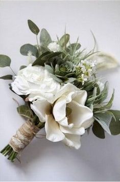 a bridal bouquet with white flowers and greenery on the stems, tied in twine