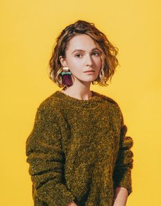 a woman in a green sweater is standing with her hands on her hips and looking at the camera