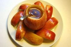 an apple that has been cut into pieces and is sitting on a plate with a spoon in it