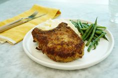 a white plate topped with meat, green beans and mashed potatoes