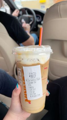 a person holding up a drink in the back seat of a car with a ticket on it