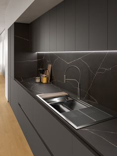 a kitchen with marble counter tops and black cabinets, along with a sink in the middle