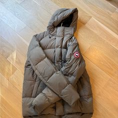 Stylish And Warm Canada Goose Puffer Jacket. Features A Hood And Signature Logo Patch. Khaki Color Looks A Little Green. Color Is Called Quicksand Hooded Puffer Jacket, Khaki Color, Signature Logo, Canada Goose, Canada Goose Jackets, Puffer Jacket, Patch Logo, Green Color, Puffer