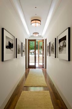 a long hallway with pictures hanging on the wall and an open door leading to another room