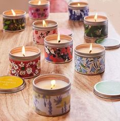 many small candles sitting on top of a wooden table next to each other in tins