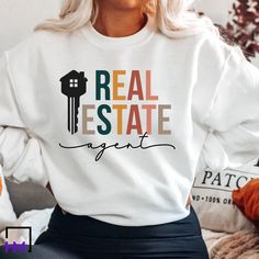 a woman wearing a white sweatshirt with the words real estate painted on it