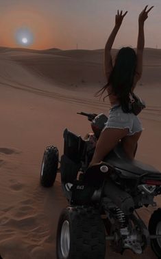 a woman riding on the back of a four wheeler atv in the desert at sunset