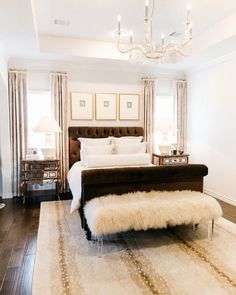 a bedroom with a bed, two nightstands and a chandelier hanging from the ceiling