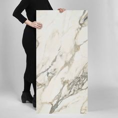 a woman holding up a large white marble slab