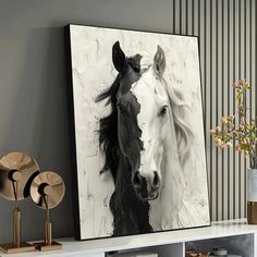 a black and white photo of a horse on a wall next to a vase with flowers