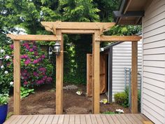 a wooden deck with a pergolated area in the middle and flowers around it