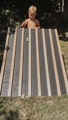 a young boy sitting at a picnic table made out of wood planks in the yard