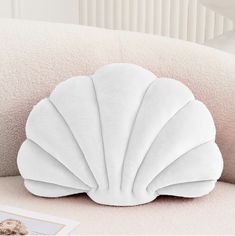 a white shell shaped pillow sitting on top of a couch next to a framed photo