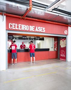 two men standing in front of a restaurant with red walls and white lettering on the door