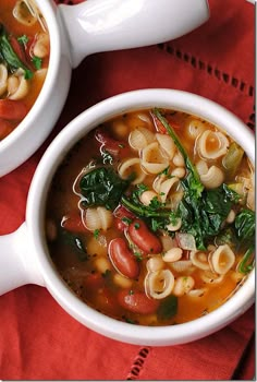 two white bowls filled with soup on top of a red table cloth next to each other