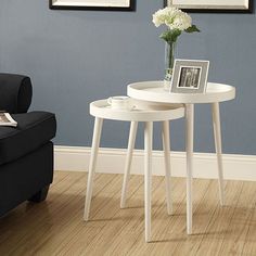 two white tables sitting on top of a hard wood floor next to a black chair