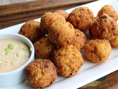 some fried food is on a white plate with a bowl of dipping sauce next to it