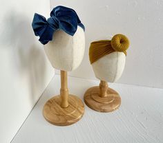 two wooden mannequins with hair bows on them sitting next to each other