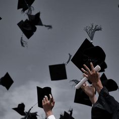 graduates throwing their caps in the air with graduation hats flying above them and holding diplomas