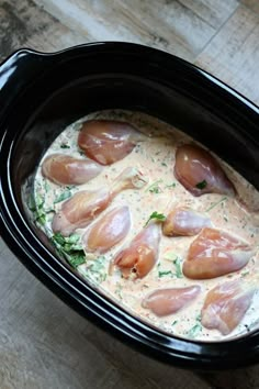 a black crock pot filled with meat and sauce