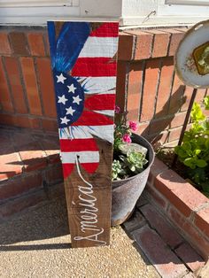 a wooden sign with an american flag painted on it next to a potted plant