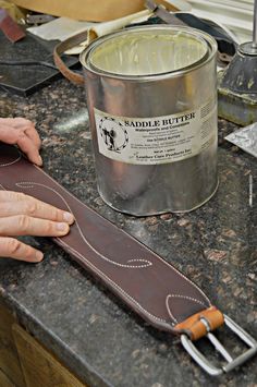 a person holding a knife near a can of butter on a counter top with other tools