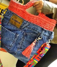 a woman is holding a purse made out of jeans