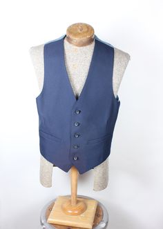 "ALL CLOTHING SALES ARE FINAL. How sharp is this vest, though? Wow. Navy polyester 5-button with perfect fit back. Back has satin coin pattern material. No smoke, mildew or damage. Please check measurements before purchasing. Measurements:  Chest: 34\" Length: 23\" Pair with many of the handsome ties available in the shop right now and save on shipping! I'm here to make you look good. What a fun item! Thank you for looking!" Fitted Vest With Snap Buttons For Work, Classic Tailored Vest With Buttons, Classic Fitted Denim Vest With Pockets, Fitted Sleeveless Sweater Vest With Button Closure, Classic Single-breasted Sleeveless Vest, Classic Denim Vest With Button Closure, Fitted Blue Denim Vest With Snap Buttons, Blue Fitted Denim Vest With Snap Buttons, Classic Navy Sleeveless Vest