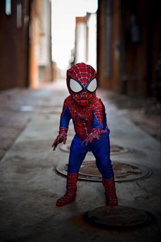 a little boy dressed up in a spiderman costume