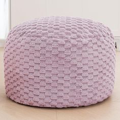 a pink round poufce sitting on top of a hard wood floor