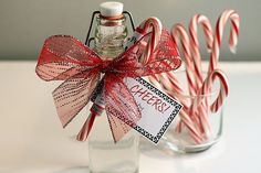 some candy canes are in a glass bottle with a tag on it and tied to the top