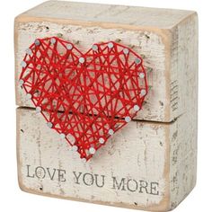 a red string art heart on top of a wooden block with words love you more