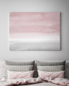 a painting hanging above a bed with pink and grey sheets on it's headboard