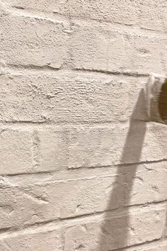 the shadow of a person's hand on a white brick wall