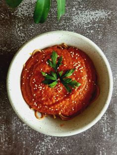 a white bowl filled with sauce and garnished with parsley on the side