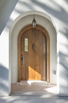 an arched wooden door with two sidelights on the outside of a white wall and floor