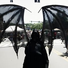 two people dressed in black are walking down the street with umbrellas attached to their heads