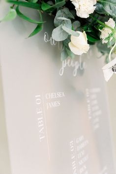 a bouquet of white flowers sitting on top of a glass plaque