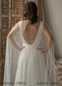 the back of a woman wearing a white wedding dress with pearls on it's shoulders