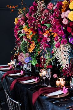 the table is set with black linens and colorful floral centerpieces on it