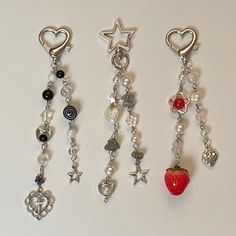 four charms with hearts, stars, and other items hanging from them on a white surface