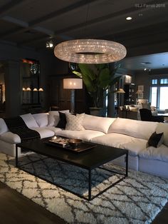 a living room filled with white furniture and a chandelier hanging from the ceiling