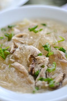 a close up of a bowl of food with broth and meat in it on a table