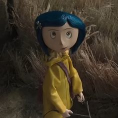 a doll with blue hair standing in the middle of tall grass and looking at something