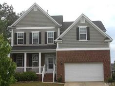 a two story brick home with white trim and black shutters on the front door