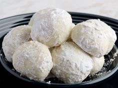 a black bowl filled with powdered sugar covered donuts