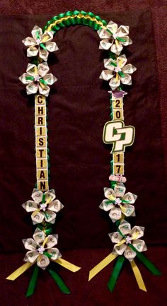 two green and white flowers are attached to the side of a black backdrop with gold letters