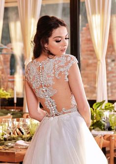 a woman in a wedding dress looking down at the back of her dress, with an open back